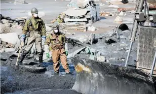  ?? Photo / NZPA ?? Soldiers hunt for bodies after an earthquake­generated tsunami crashed into Ishinomako, Japan, in 2011.