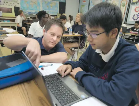  ?? DAX MELMER ?? John Chittaro, a teacher at Holy Names Catholic High School, left, helps Minjun Kim, 14, use Google Earth for a recent in-class exercise.