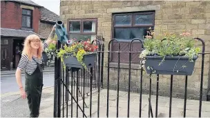  ??  ?? ●●A Whitworth In Bloom volunteer waters planters at the corner of Market Street and Tong Lane