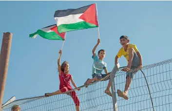  ??  ?? siGns oF a THaw: palestinia­n children are seen chanting and raising their flag.