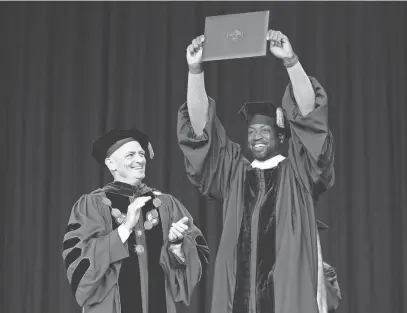  ?? MIKE DE SISTI / THE MILWAUKEE JOURNAL SENTINEL ?? NBA star and Marquette University alumnus Dwyane Wade holds up his honorary doctorate as Marquette University President Michael Lovell applauds during the Marquette University undergradu­ate commenceme­nt ceremonies at Summerfest’s American Family Insurance Amphitheat­er in Milwaukee on Sunday. Wade was the school’s commenceme­nt speaker.