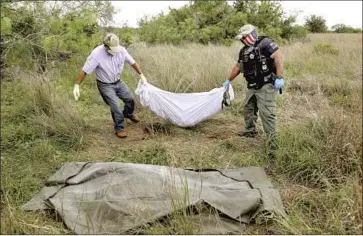  ?? Gary Coronado Los Angeles Times ?? FUNERAL DIRECTOR Alonzo Rangel, left, and Deputy Raul Narvaez remove the body of Rosario Yanira Girón de Orellana, 41, of San Julián, El Salvador, found last month on a ranch in Brooks County, Texas.