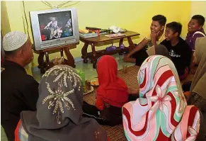  ??  ?? Big moment: Mohd Nawi watching the installati­on ceremony with his family at his home in Pasir Mas.