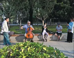  ?? ?? A foreign artist playing the cello by the Liangma River in Sanlitun, attracting pedestrian­s to watch, June 14, 2022.