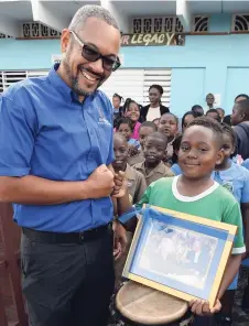  ?? JERMAINE BARNABY/FREELANCE PHOTOGRAPH­ER ?? Justin Reid is holding an autographe­d photo of himself and Usain Bolt, which was presented to him by Christophe­r Barnes, managing director of The Gleaner, on Wednesday as he shares a fist bump with Barnes.