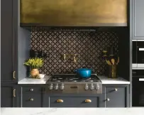  ?? HOEDEMAKER PFEIFFER ?? In the kitchen of this Seattle project done by design/ build firm Hoedemaker Pfeiffer, the cabinets were painted SherwinWil­liams’ Iron Ore. Brushed metallic taps, hardware and range hood, and an artful backsplash, add atmosphere and interest to the vignette.