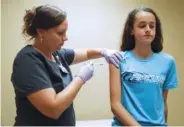  ??  ?? Nurse Laura Johnson administer­s a dose of the HPV vaccine to Abby Major.