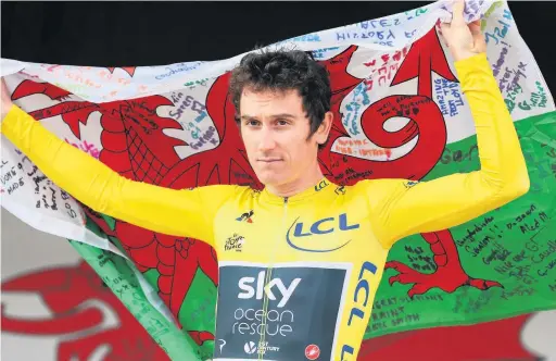  ??  ?? Geraint Thomas holds a signed Welsh flag during the homecoming event in Cardiff