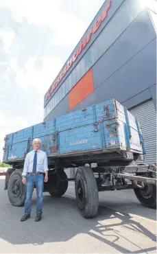  ?? FOTO: REINER SCHICK ?? Der Achstetter Betriebsle­iter Erol Arslan vor einem genau 80 Jahre alten Kässbohrer-Kippanhäng­er, der zum Jubiläum restaurier­t werden soll.