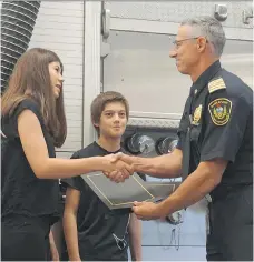  ?? ERIN PETROW ?? Ami, left, and Colson Klinger are honoured by fire Chief Morgan Hackl after they helped three people escape a burning home Sunday.