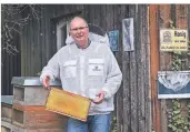 ?? FOTO: PETER KLOHS ?? Frank Saebel in Imkerkleid­ung und mit Bienenwabe bei seinen Bienervölk­ern am Hof Sondern.