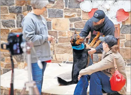  ?? [BRYAN TERRY/THE OKLAHOMAN] ?? Kyle Kerr and his wife, Kasey, look at a dog named Gavin with Cindy Kienlen, a volunteer with Pets and People, during an adoption day to bring awareness to Black Dog Syndrome.