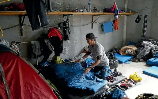  ?? TNS. ?? Kevin Roney Hernandez Melgar arranges his bedding in his sleeping area at the El Barretal migrant shelter in Tijuana. Melgar is among 12 men who share a living space at the shelter while waiting to enter the United States.