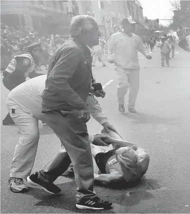  ?? PHOTOS: THE ASSOCIATED PRESS ?? Marathon officials help a competitor who fell when a second explosion rocked the Boston Marathon on Monday.