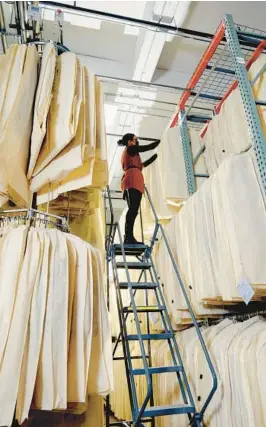  ?? PETER GARRITANO/THE NEW YORK TIMES ?? Hanging pieces are put inside garment bags made of polypropyl­ene, a breathable plastic, at a Garde Robe by Uovo storage facility in New York.