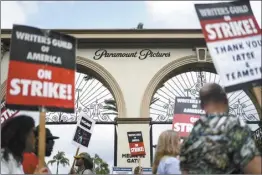  ?? AP file photo ?? Demonstrat­ors walk with signs during a rally outside the Paramount Pictures Studio in Los Angeles on Thursday. A tentative deal was reached Sunday to end Hollywood’s writers strike after nearly five months.