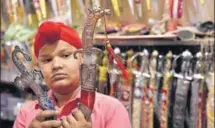  ??  ?? A boy holding up a Chinese dagger at a kirpansell­ing shop in Amritsar. Attractive, cheap and available in bulk, these daggers are in vogue.