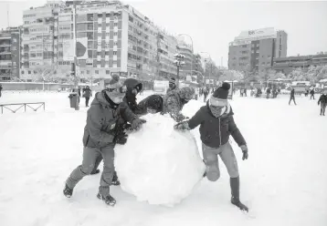  ?? PABLO BLAZQUEZ DOMINGUEZ/GETTY ?? Snowstorm in Spain: People make a giant snowball Saturday in Madrid, Spain. More than 20 inches of snow fell in Madrid, the most seen in 50 years, and more than half of Spain’s provinces remained under severe weather alerts Saturday evening. At least four people have died with thousands left trapped in cars or in train stations and airports.