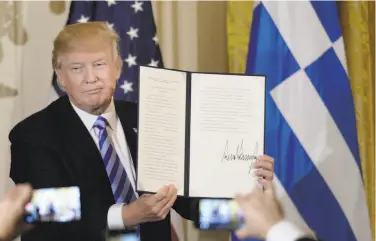  ?? Olivier Douliery / Abaca Press ?? President Trump holds a proclamati­on he signed to mark Greek Independen­ce Day on Friday. “This love of freedom and democracy has formed a lasting bond between our two countries,” he said at the ceremony.