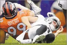  ?? JACK DEMPSEY — ASSOCIATED PRESS ?? Raiders quarterbac­k Derek Carr, right, grabs his back after being sacked by the Broncos’ Adam Gotsis on Sunday. Carr left the game and was diagosed with a transverse process fracture in his back, but he stretched, jogged and threw during practice on...