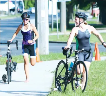  ??  ?? Ashlee Diston and Molly Irvine transition to the bike during Wild Dog Triathlon Club’s senior race.
