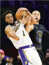  ?? JAE C. HONG Associated Press ?? TROY BROWN JR., left, and Stephen Curry battle for the ball. Curry scored 27 in his return.