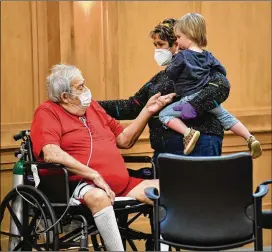  ?? PHOTOS BY HYOSUB SHIN/ HYOSUB. SHIN@ AJC. COM ?? Larry Schepps touches his great- granddaugh­ter, Penton Schepps, as Ann Schepps, his daughter- in- law, visits him at the Breman Jewish Home.