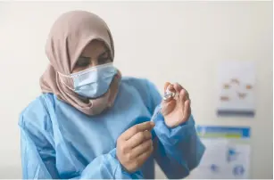  ?? (Mohammed Salem/Reuters) ?? A PALESTINIA­N health worker prepares a vaccinatio­n against coronaviru­s in Gaza City yesterday.