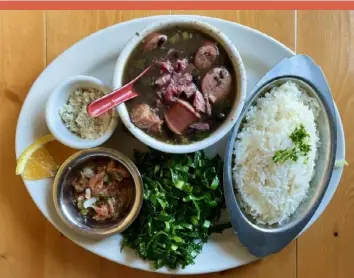  ?? Hal B. Klein/Post-Gazette photos ?? Feijoada completa, pork and black bean stew with pork shanks, smoked sausage, bacon and black beans, served with ice, stir-fry collard greens, farofa, oranges and Brazilian vinaigrett­e at Casa Brasil.