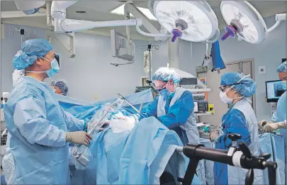  ?? CP PHOTO ?? Surgeons work on a hip replacemen­t procedure in this undated handout photo. Patients whose emergency surgeries are delayed due to a lack of operating room resources have an increased risk of death or a need for extra recovery time in hospital, a...