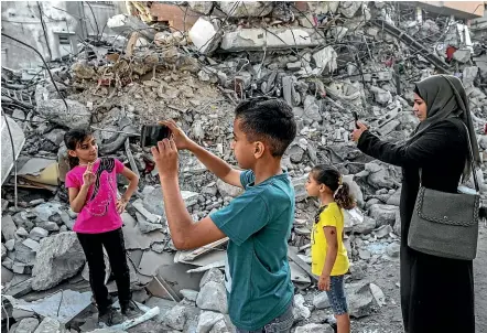  ?? GETTY IMAGES ?? A Palestinia­n girl poses for photos in front of the rubble of a building in Gaza City, after the ceasefire between Israel and Hamas militants took effect. Aid agencies say a humanitari­an crisis is brewing in Gaza, with the territory’s electricit­y and water systems damaged, and food and medical supplies held up at border checkpoint­s.