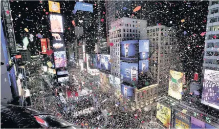  ??  ?? > Confetti drops over the crowd as the clock strikes midnight in Times Square, New York