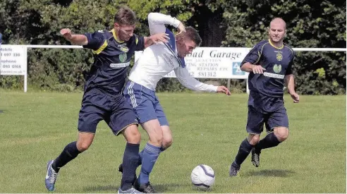  ??  ?? Danny Roberts (dark blue) puts in a tackle against Trearddur Bay last Saturday as team-mate John Blundell looks on. The match ended 2-2. Pic: STEVE LEWIS.