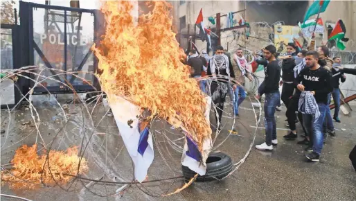  ?? PHOTOS BY BILAL HUSSEIN/ AP ?? Protesters burn an Israeli flag at the U. S. Embassy in Aukar, Lebanon, on Sunday. Demonstrat­ors threw stones and burned an effigy of President Trump to protest Washington’s recognitio­n of Jerusalem as Israel’s capital.