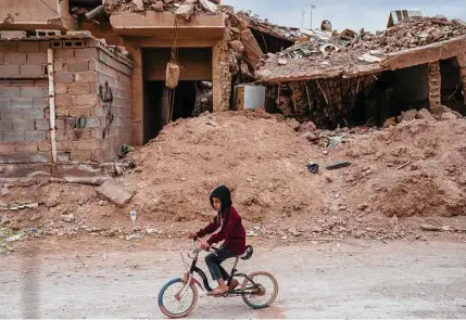  ?? Joao Silva/New York Times ?? A child on March 8 passes a building in Fallujah, Iraq, that was destroyed as Iraqi fighters wrested control of the city from the Islamic State in 2016. Much of Iraq bears the scars of two decades of violence.