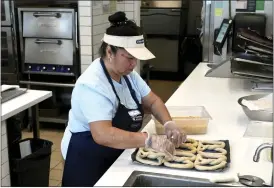  ?? TERRY CHEA — THE ASSOCIATED PRESS ?? An employee makes pretzels at Auntie Anne’s and Cinnabon in Livermore on Thursday. She’s among hundreds of thousands of California fast-food workers now earning a higher wage.