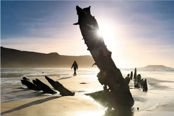  ??  ?? ▲ HERE BE MONSTERS Stripped of its hull by salvagers and the sea, the halfenvelo­ped skeleton of the Helvetia lies forlorn on Rhossili Bay, with Worms Head behind.