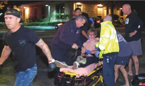  ?? AP ?? A victim is treated near the scene of a shooting Wednesday evening in Thousand Oaks, California. A hooded gunman opened fire on a crowd at a country dance bar holding a weekly ‘college night’ in Southern California, killing multiple people.