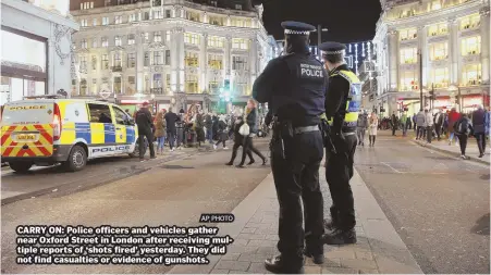  ?? AP PHOTO ?? CARRY ON: Police officers and vehicles gather near Oxford Street in London after receiving multiple reports of ‘shots fired’ yesterday. They did not find casualties or evidence of gunshots.