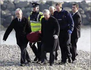  ??  ?? Gardaí and undertaker­s removing the man’s remains from the beach last week.