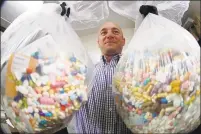  ?? Associated Press ?? Ben Hill, an Ohio narcotics detective, holds up two bags of medication­s that are currently being stored and are slated for destructio­n in Barberton, Ohio.