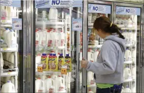  ?? SUE OGROCKI — THE ASSOCIATED PRESS FILE ?? Jessica Walton of Guthrie, Okla., reaches for a container of milk at a grocery store in Edmond, Okla. On Tuesday, Dean Foods, the nation’s largest milk processor, filed for Chapter 11 bankruptcy protection and said it may sell the company off to the Dairy Farmers of America.