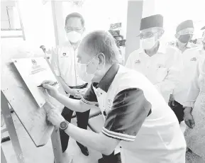  ?? — Gambar Bernama ?? RASMI: Wan Junaidi menandatan­gani plak perasmian pada Majlis Perasmian Bangunan Klinik Ibu dan Anak Bintawa Kuching, semalam.