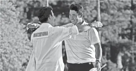  ?? MICHAEL MADRID/USA TODAY SPORTS ?? Hideki Matsuyama celebrates with his caddie Shota Hayafuji on the 18th green after winning the Masters on Sunday.