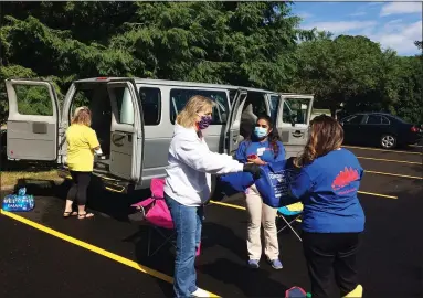  ?? CHAD FELTON — THE NEWS-HERALD ?? Lake County Treasurer Lorraine M. Fende, foreground, left, receives care kits from Meijer employees at Mentor Public Library’s Main Branch on June 24. In lieu of its Annual Day of Caring, UWLC collected various kits at five locations across the county to help those in need.