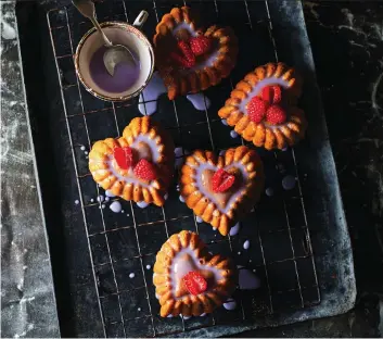  ?? PHOTOS: ALAN BENSON/POH BAKES 100 GREATS ?? Poh Ling Yeow’s heart-shaped mini cakes have a delicious orange flavour and are topped with a violet glaze and raspberrie­s — perfect for a tasty Valentine’s Day treat.