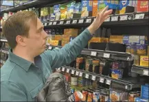  ?? AP photo ?? Stuart Dryden reaches for an item at a grocery store on Wednesday, Feb. 21, 2024, in Arlington, Va. Dryden is aware of big price disparitie­s between branded products and their store-label competitor­s, which he now favors.