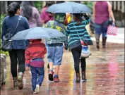  ?? Katharine Lotze/ ?? Shoppers stroll under umbrellas at Westfield Valencia Town Center during a brief rainshower Monday.