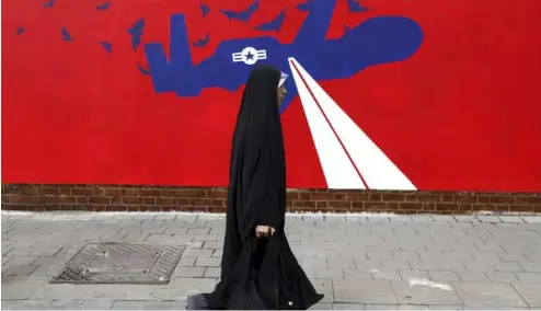  ?? ?? Eine Frau geht an einem neuen Anti-US-Wandbild an der Wand der ehemaligen US-Botschaft in Teheran vorbei, 2019.