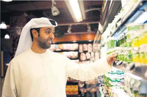  ?? Sarah Dea / The National ?? Rashid Aljari shops for goat’s milk to feed his lactose intolerant son at The Organic Foods & Café in Dubai Mall.
